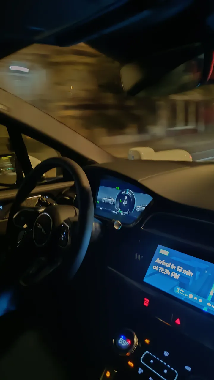 The interior of a moving, autonomous Waymo car at night, with the illuminated dashboard and a center screen showing an "Arrival in 13 min" message.